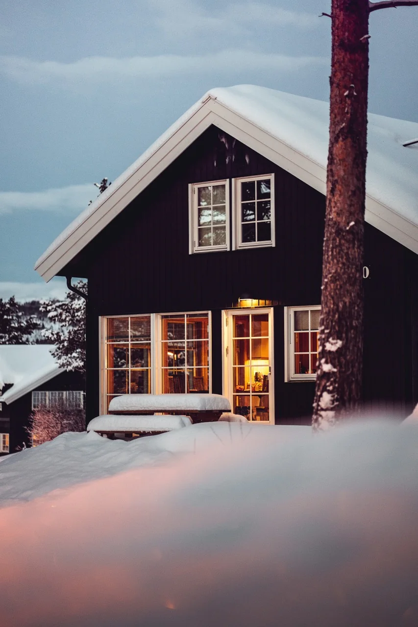 Opplyst trehus i et snødekt landskap som eksempel på utvendig boligfoto